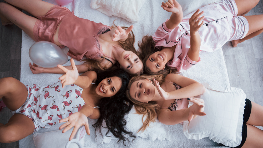 air kisses top view young girls bachelorette party lying sofa raising their hands up