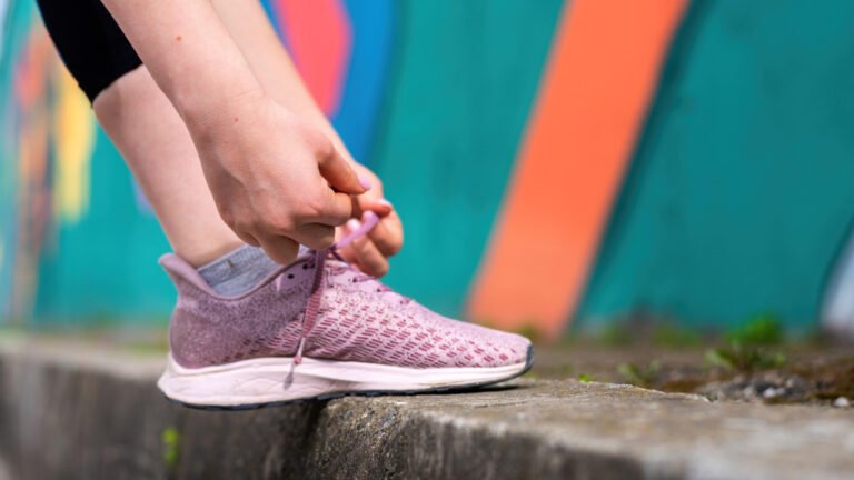 Como montar um look com tênis rosa? 1 young woman tying her shoelaces outdoors training road